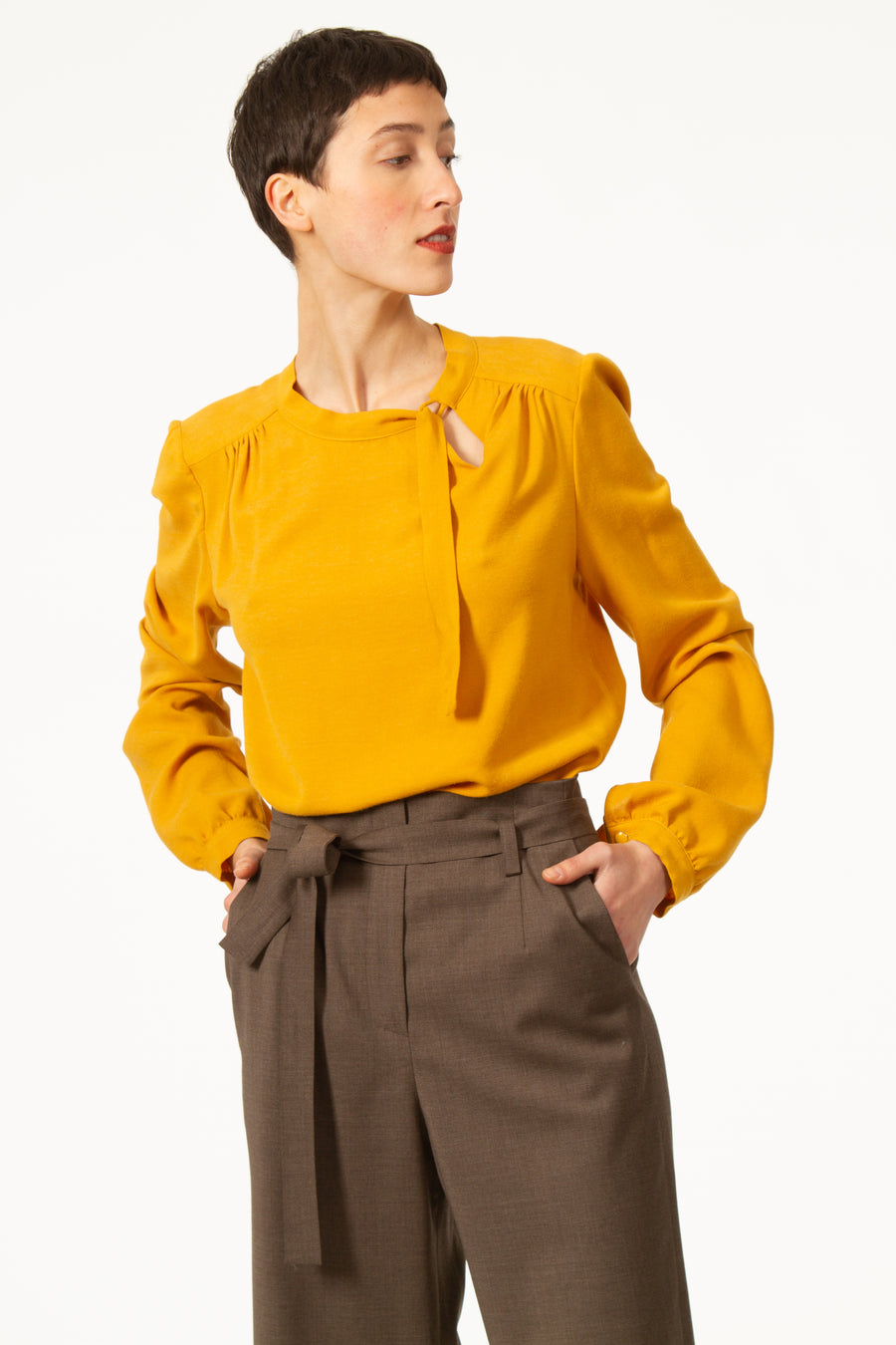 Top JEAN Jaune à col rond et noué sur le côté. Blouse asymétrique en voile viscose laine. Empiècement sur le dos et les épaules. Manches longues avec poignets boutonnés.