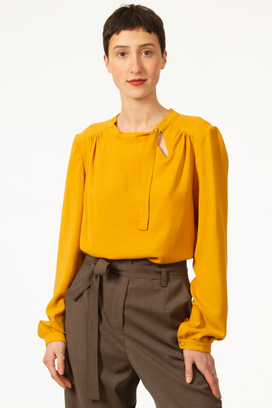 Top JEAN Jaune à col rond et noué sur le côté. Blouse asymétrique en voile viscose laine. Empiècement sur le dos et les épaules. Manches longues avec poignets boutonnés.