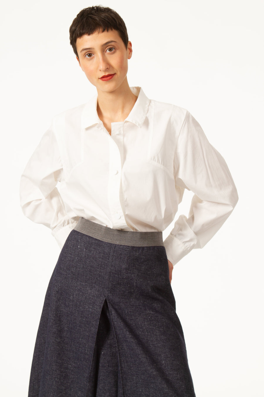 Jupe MARC Bleue légèrement évasée en jean de laine. Taille haute resserrée par une bande grise. Fente devant. Longueur genou. Zip derrière.