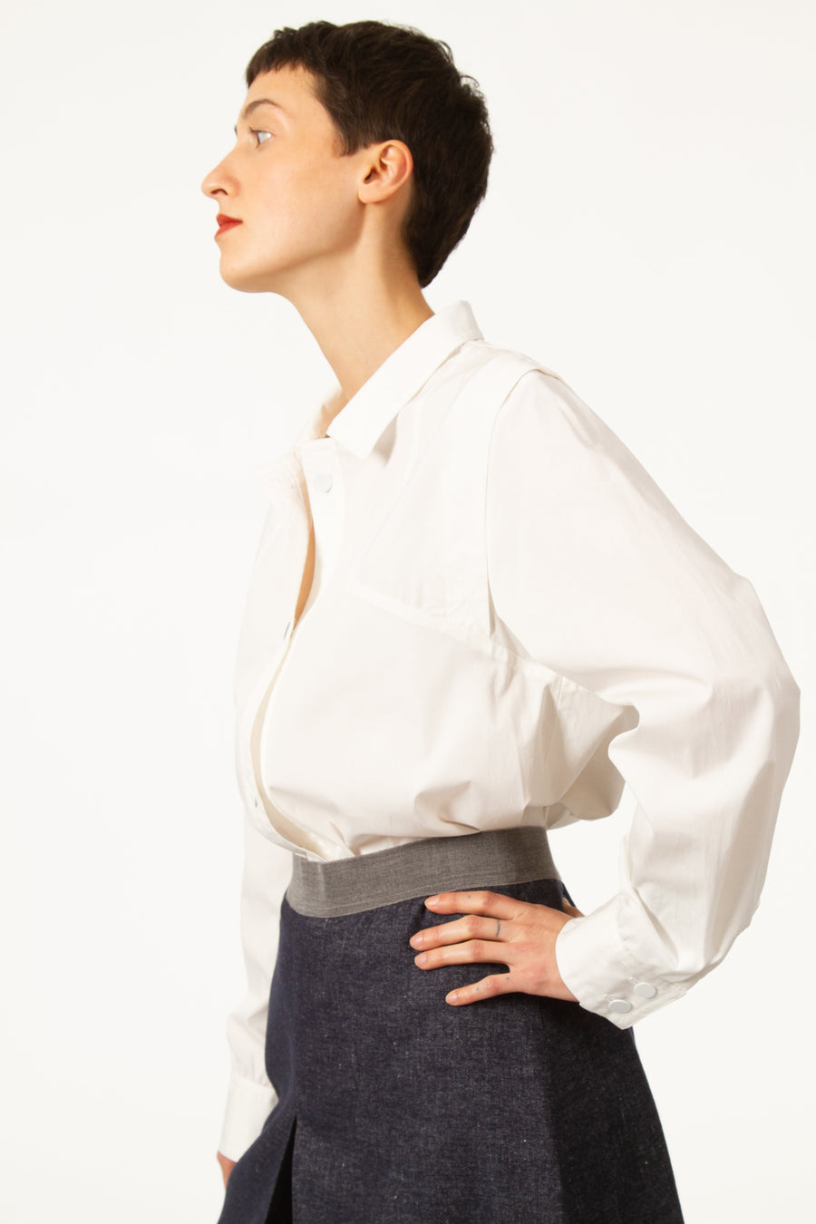 Jupe MARC Bleue légèrement évasée en jean de laine. Taille haute resserrée par une bande grise. Fente devant. Longueur genou. Zip derrière.
