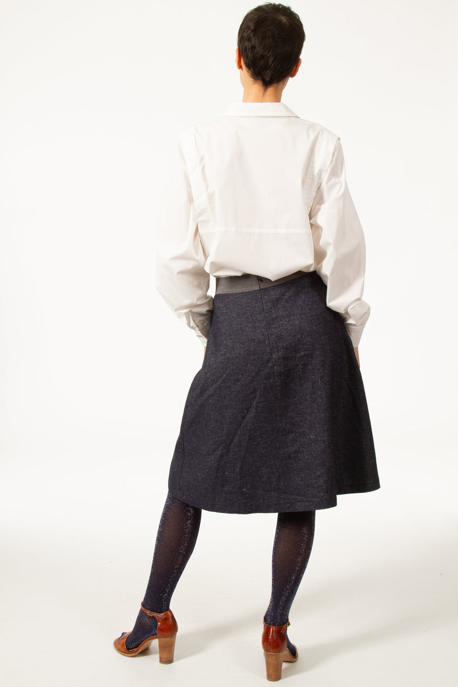 Jupe MARC Bleue légèrement évasée en jean de laine. Taille haute resserrée par une bande grise. Fente devant. Longueur genou. Zip derrière.