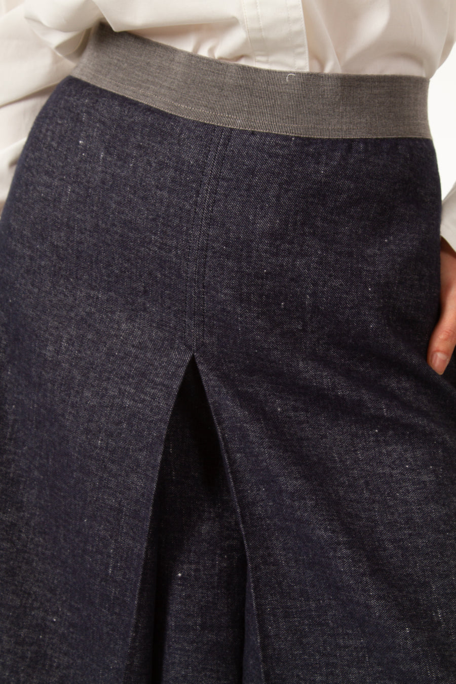 Jupe MARC Bleue légèrement évasée en jean de laine. Taille haute resserrée par une bande grise. Fente devant. Longueur genou. Zip derrière.